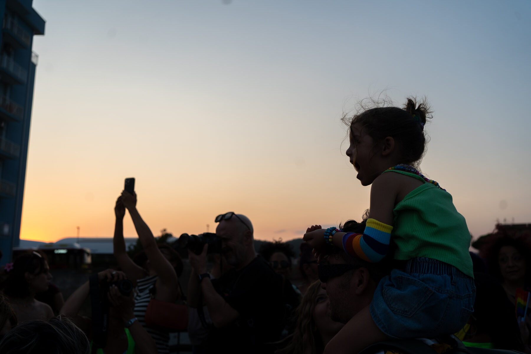 Un bambino sulle spalle di un adulto guarda il tramonto durante il Catanzaro Pride