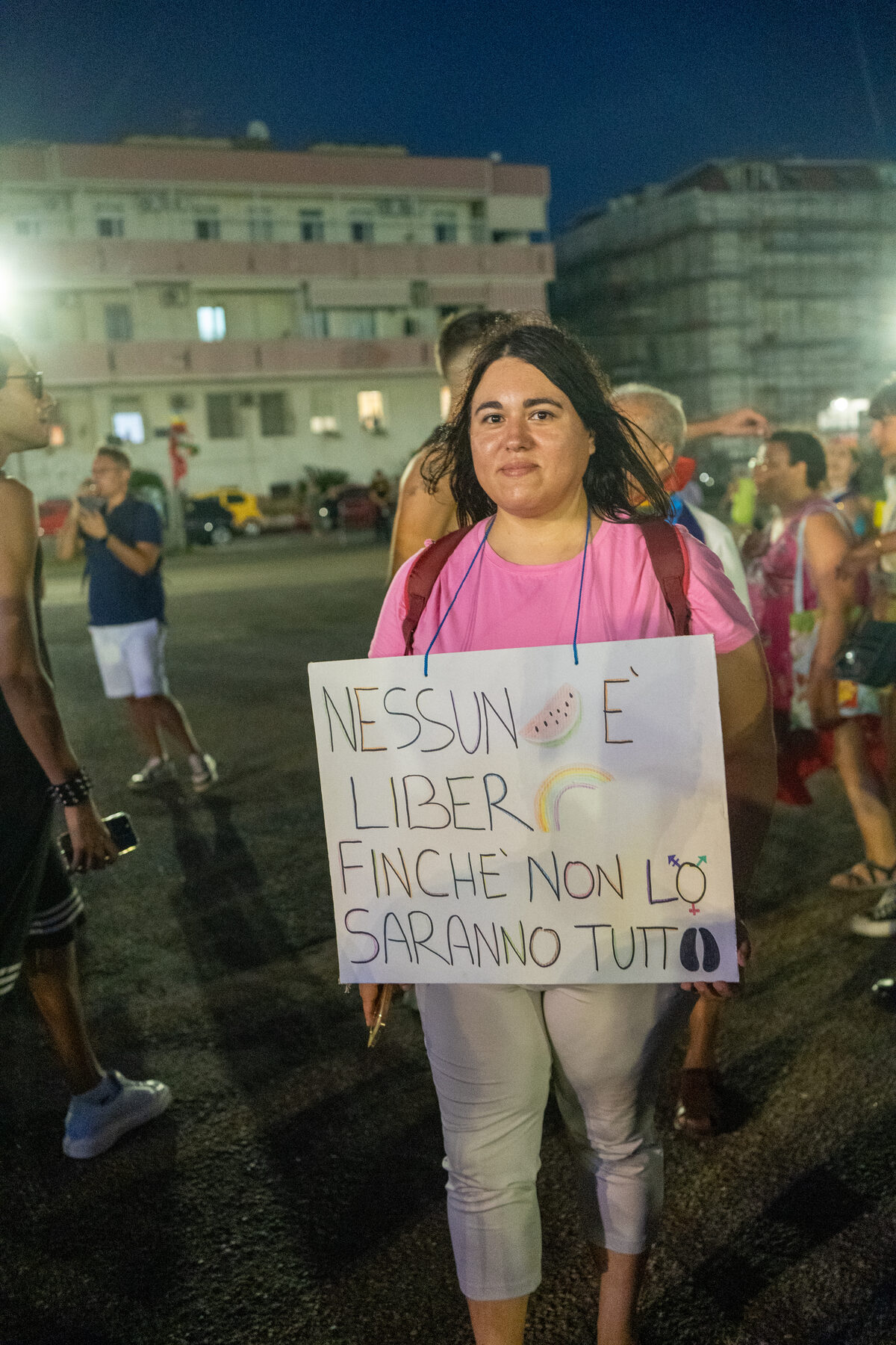 Una manifestante mostra un cartello con la scritta Nessuno è libero finché non lo saranno tutti