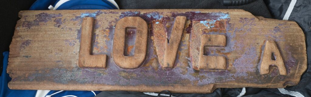 Tavola di legno del caicco Summer Love con le lettere in rilievo LOVE A, raccolta sulla spiaggia di Steccato di Cutro e conservata da Bruno Palermo.
